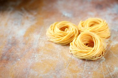 Ahşap bir masada un ile ham ev yapımı spagetti yuva. Taze 