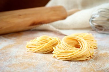 Ahşap bir masada un ile ham ev yapımı spagetti yuva. Taze 