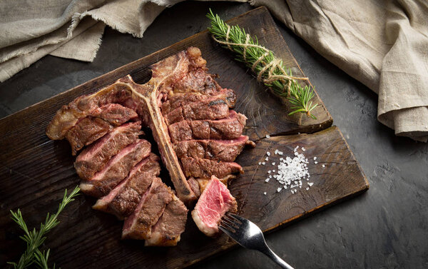 Porterhouse steak is grilled sliced on a piece of wood Board. rustic style, top view