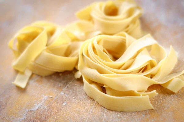 Fresh fettuccine pasta on a wooden table with flour — Stock Photo, Image