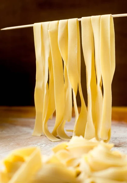 Fresh fettuccine pasta on a wooden table with flour — Stock Photo, Image