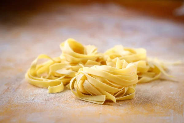 Fresh fettuccine pasta on a wooden table with flour — Stock Photo, Image