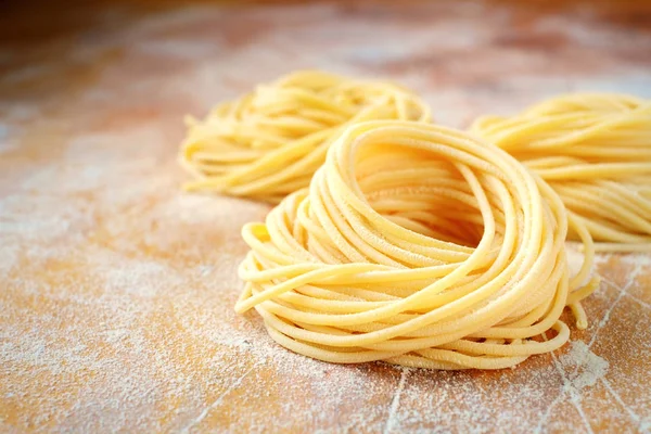 Raw homemade spaghetti pasta nest with flour on a wooden table. fresh — Stock Photo, Image