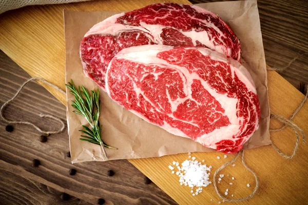 Hazırlanan bir masada ahşap bir Tahta üzerinde iki çiğ kaburga göz biftek — Stok fotoğraf