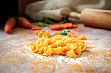 ahşap bir masada havuç ile taze ev yapımı conchiglie makarna