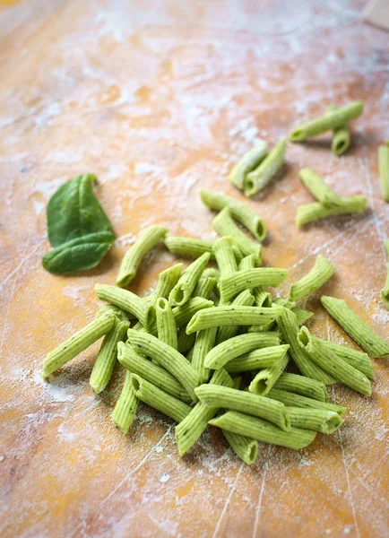 Uncooked homemade green spinach pasta on wooden table