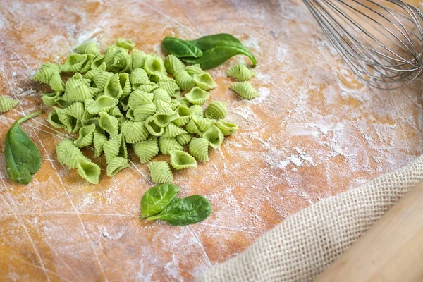 Uncooked homemade green spinach pasta on wooden table, top view