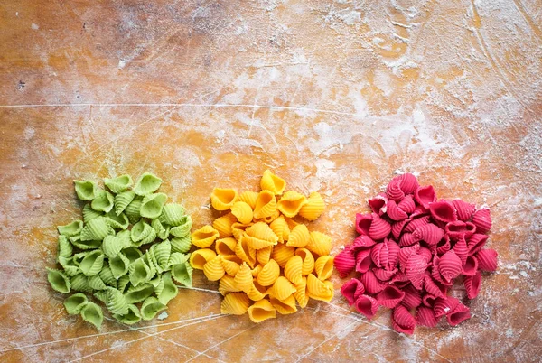 Сырая цветная макароны на кухне деревянный стол с мукой — стоковое фото