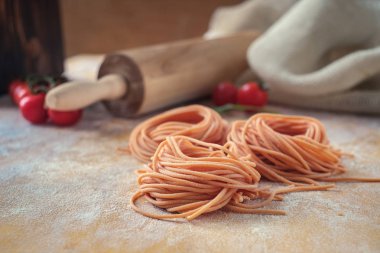 ahşap bir masa üzerinde un ile ham ev yapımı renkli spagetti yuva