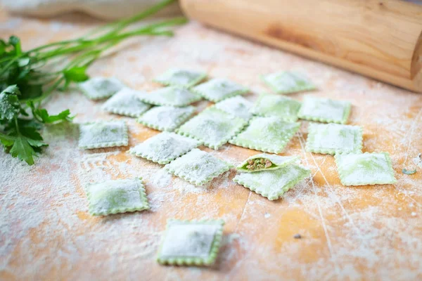 traditional raw ravioli with spinach and meat on a wooden table