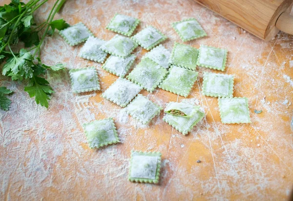 traditional raw ravioli with spinach and meat on a wooden table