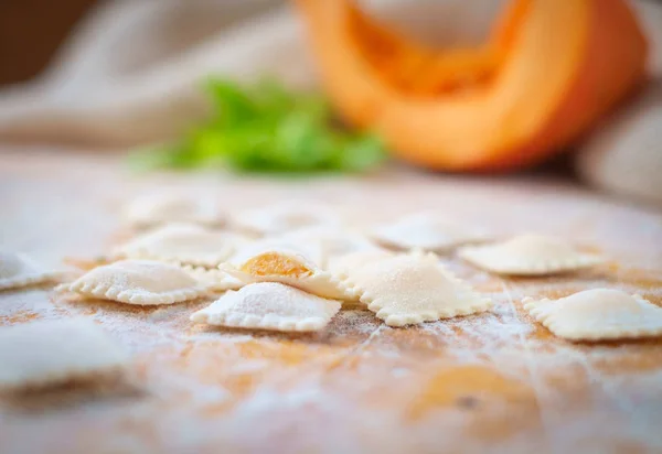 traditional raw ravioli with pumpkin on a wooden table