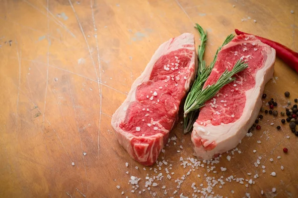 Raw beef sirloin Steak with seasoning on yellow wooden