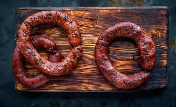 Smoked round ring beef sausages on wooden board