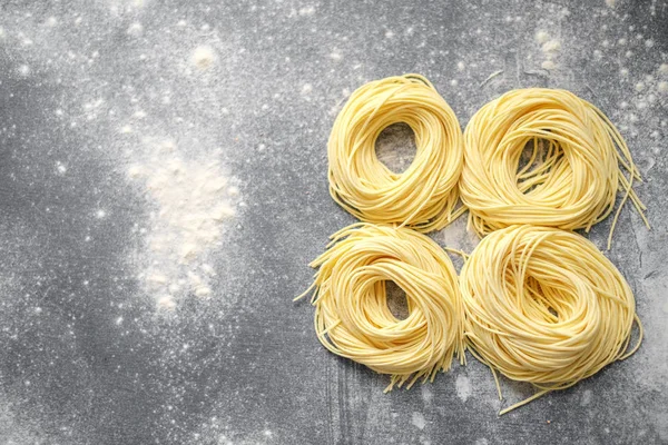 Сире домашнє гніздо спагетті з борошном на сірому фоні — стокове фото