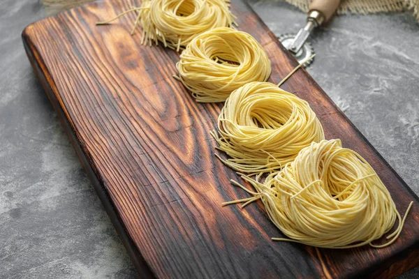 Nests of spaghetti on a wooden Board at the time of cooking home — Stock Photo, Image