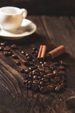 kahve çekirdekleri ve ahşap koyu arka plan üzerinde beyaz kupa. 