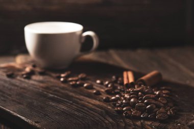 kahve çekirdekleri ve ahşap koyu arka plan üzerinde beyaz kupa.