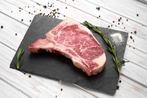 Rohe Club-Steak auf einem Steinbrett auf weißem Holzhintergrund — Stockfoto