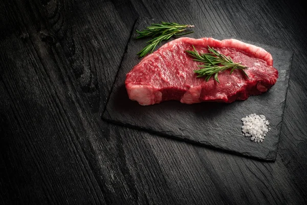 siyah ahşap arka plan üzerinde ham taze şerit bel biftek 