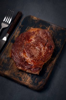 Izgara pirzola bifteği, ahşap tahtada çıtır çıtır, siyah arka planda, köy usulü.