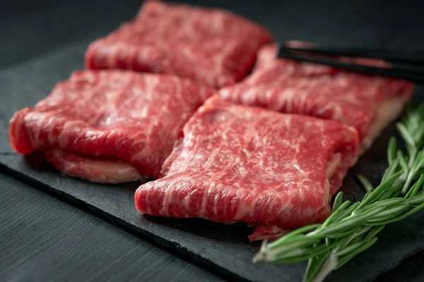 Premium raw Black Angus beef minute steak on Black wooden background. Slice wagyu for yakiniku