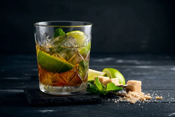 Siyah rom, limon ve naneli kokteyl, Brezilya Caipirinha alkollü koyu ahşap içki.