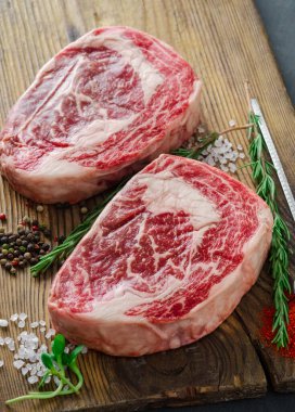 Kasap kurulunda pişmeye hazır ahşap bir masada iki çiğ biftek. Mermer biftek.