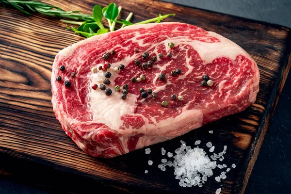 黒地に板紙に塩コショウをかけた牛肉の生リブステーキ — ストック写真