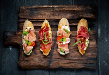 Geleneksel, Parma kurutulmuş jambon ve prosciutto. Jamonlu İtalyan antipasti sandviçleri, süzme peynir, roka ve kırsal ahşap tahta üst görüşlü güneşte kurutulmuş domatesler.