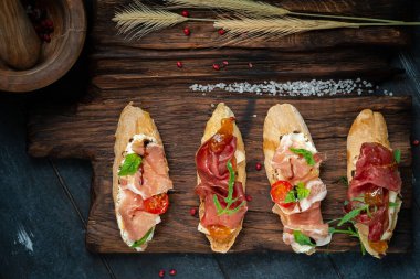 Geleneksel, Parma kurutulmuş jambon ve prosciutto. Jamonlu İtalyan antipasti sandviçleri, süzme peynir, roka ve kırsal ahşap tahta üst görüşlü güneşte kurutulmuş domatesler.