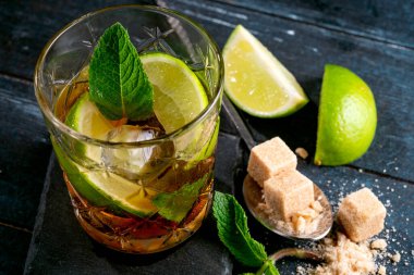 Viski ve kola kokteyli limon, nane, esmer şeker ve buz, koyu ahşap arka planda bir bardakta alkollü içecek, kopyalama alanı.