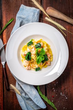 Deniz mahsullü Tagliatelle. Geleneksel İtalyan makarnası, beyaz tabakta krema soslu fesleğen. Üst görünüm