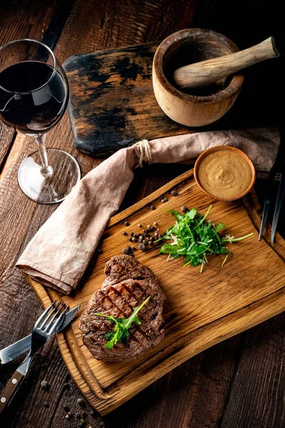 Grilled chuck beef steak with wine, knife and fork on a wooden Board. Whole roast piece of meat, close up and rustic style