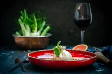 Kurutulmuş domatesli burata peyniri enginar, roka ve kırmızı tabakta fesleğen. İtalyan mutfağı aperatiftir..