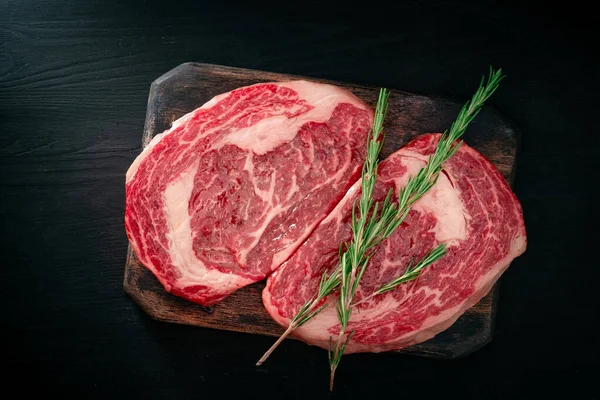 Ideales Roh Rib Eye Rindersteak Mit Rosmarin Auf Schwarzem Holzhintergrund — Stockfoto