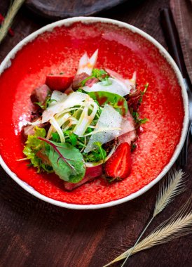 Ahşap bir zeminde sığır filetosu, roka, ıspanak, çilek ve parmesan salatası. İtalyan mutfağı kırsal tarzı