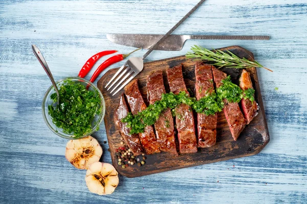 Chimichurri soslu sulu biftek ve ahşap tahtada baharatlar..
