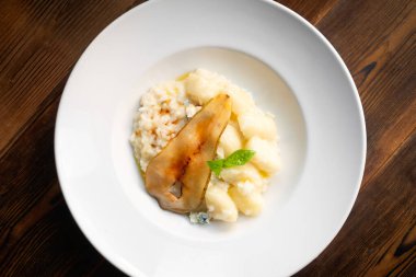 Beyaz tabakta armut ve Gorgonzola ile risotto. İtalyan yemekleri restoranda servis edilir.