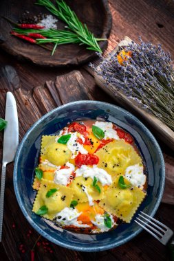 Ahşap bir arka planda domates, fesleğen ve krem peynirli renkli ravioli. İtalyan usulü makarna.