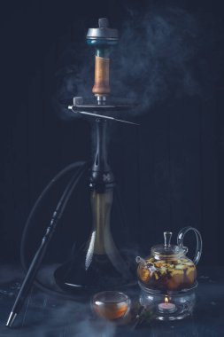 Koyu ahşap arka planda limonlu bir çaydanlık ve nargile. Geleneksel Arap shisha 'sı