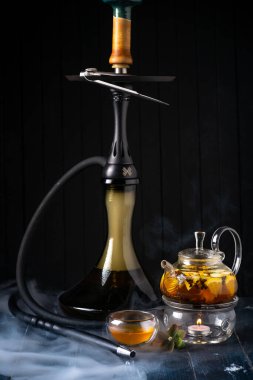 Koyu ahşap arka planda limonlu bir çaydanlık ve nargile. Geleneksel Arap shisha 'sı