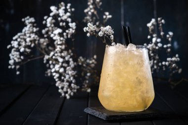 Buzlu ve çiçekli bir bardakta ananaslı ferahlatıcı bir kokteyl.