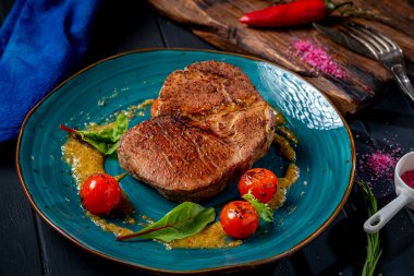 Çeri domatesli büyük ızgara biftek ve ahşap arka planda hardal.