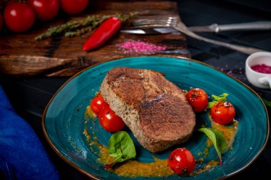 Çeri domatesli büyük ızgara biftek ve ahşap arka planda hardal.