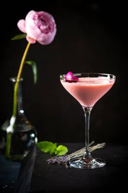 Güllerle süslenmiş pembe alkollü kokteyl ve fotokopi alanı olan siyah arka planda nane şekeri. Bar menüsü için pembe içecek