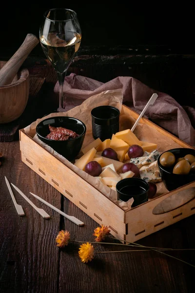 ワインの前菜 素朴なスタイルで木の背景に様々なチーズや軽食のセット — ストック写真