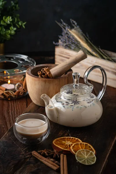 Milk spicy Indian tea Masala in a teapot with cinnamon, cloves and anise. Oriental tea ceremony on wooden background