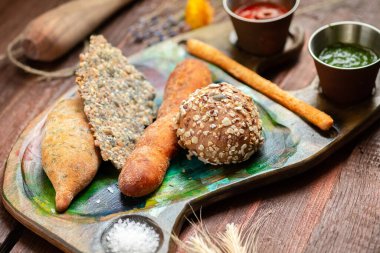 Ahşap arka planda bir tepside kırsal tarzda çeşitli ev yapımı ekmek ve hamur işleri.