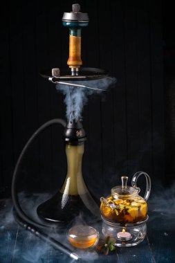 Koyu ahşap arka planda limonlu bir çaydanlık ve nargile. Geleneksel Arap shisha 'sı